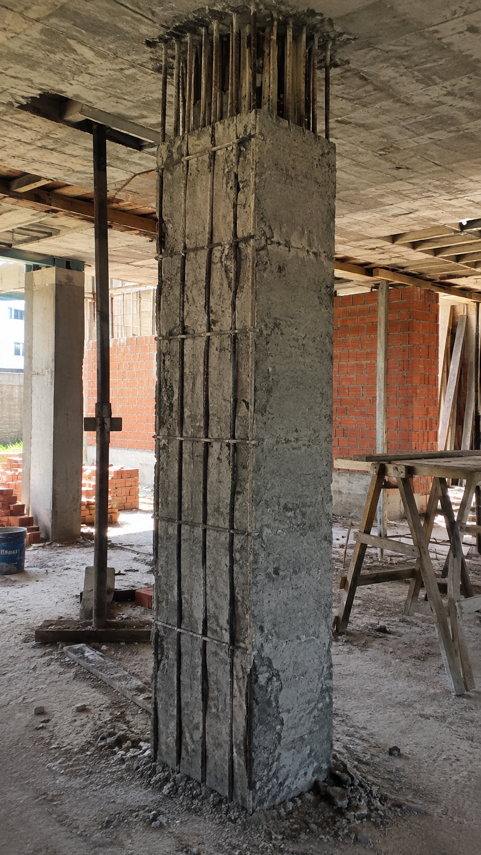 Columna de concreto con varillas de acero expuestas y zonas mal vibradas, documentada en una pericia tecnica para determinar su estabilidad.